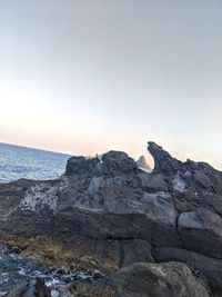 Rock formations on shore against clear sky