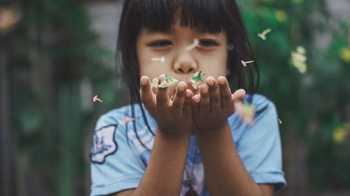 Close-up of girl blowing flowers in yard