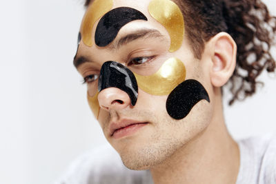 Close-up portrait of smiling young man wearing mask against white background