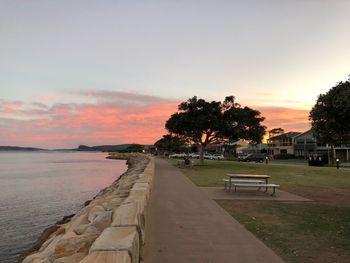 Footpath by sea against sky during sunset