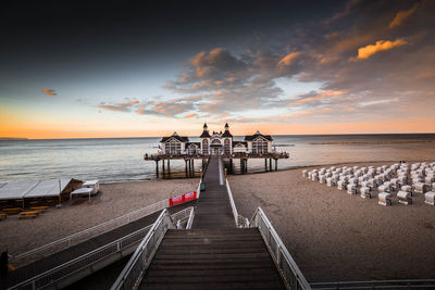 Pier on beach during sunset