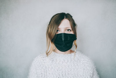 Portrait of woman standing against white wall