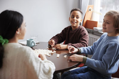 Girl and boys playing scrabble at dining table