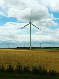 Windmills on field against sky