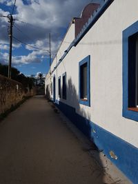 Empty street amidst buildings in city against sky