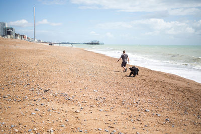 Man walking on beach against sky