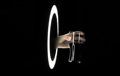 Close-up of hand holding drink against black background
