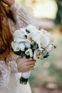 Midsection of woman holding white flowering plant