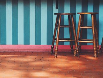 Stools on footpath against wall