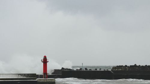 Lighthouse by sea against sky