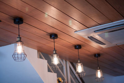 Low angle view of illuminated pendant lights hanging from ceiling