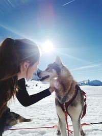 Woman with dog on snow against sky