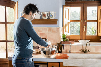 Middle aged man mixing ingredients in dough to cook homemade pastry