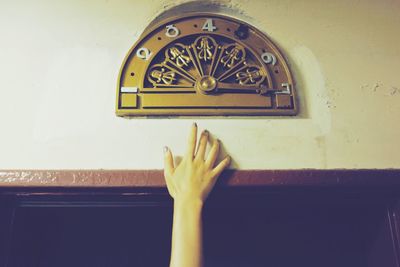 Cropped image of hand by elevator floor indicator on wall