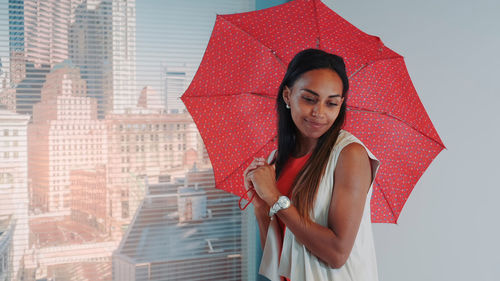 Portrait of beautiful young woman standing against red wall