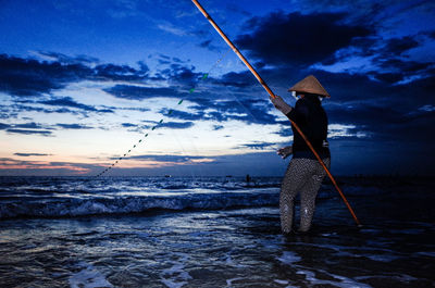 Man fishing in sea against sky