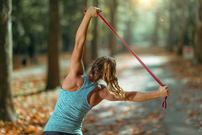 Woman exercising with elastic band outdoors in the fall, in public park