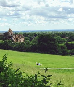 Scenic view of green landscape against cloudy sky