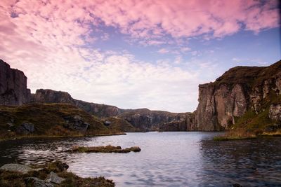 Scenic view of river and rocky mountains against sky during sunset