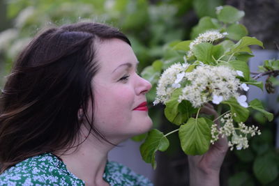 Close-up of smiling woman smelling flowers
