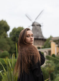 Portrait of smiling young woman standing against sky