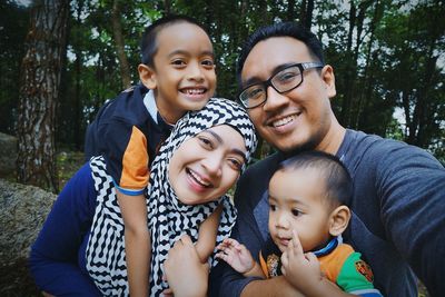 Portrait of happy family with boy against trees