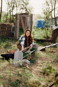 Young woman using mobile phone while sitting on field