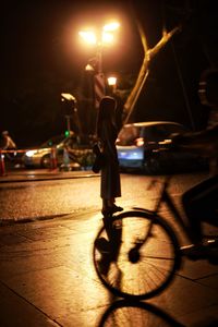 Low section of man standing on illuminated bicycle at night