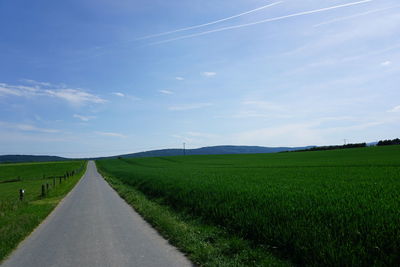 Road amidst agricultural field against sky