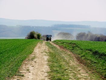 Tractor on dirt road amidst agricultural field