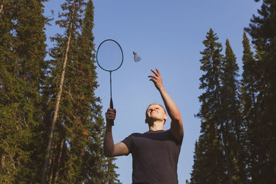 Low angle view of man playing badminton against sky