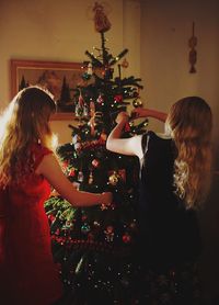 Siblings decorating christmas tree at home