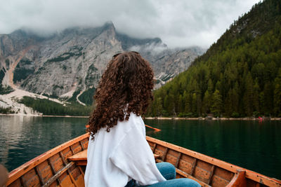 Rear view of woman looking at lake against mountains