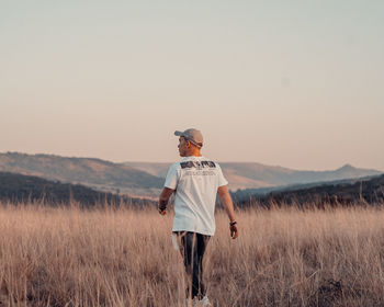 Rear view of man standing on field against sky