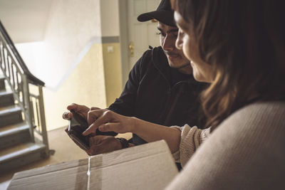 Female customer signing on smart phone during package delivery