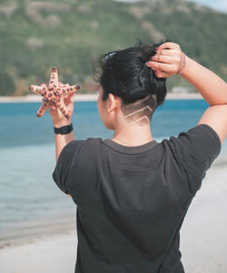 Cropped hand of woman holding seashell at beach