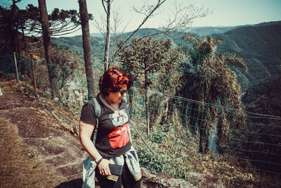 Young woman looking away while standing on railing in forest