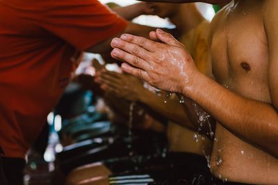 Midsection of shirtless man washing hands with water