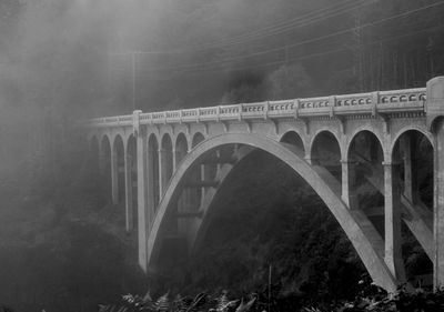 Arch bridge over valley during foggy weather