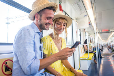 Smiling couple using smart phone sitting in bus