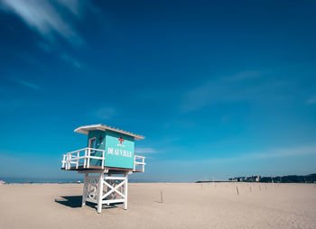 Lifeguard hut on beach against blue sky