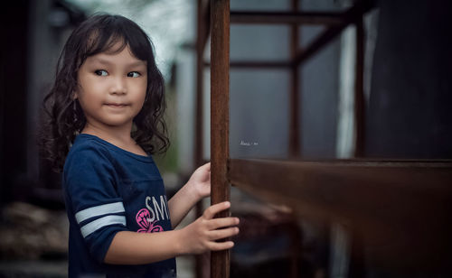 Portrait of cute girl standing against curtain