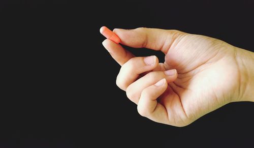 Close-up of person holding hands over black background