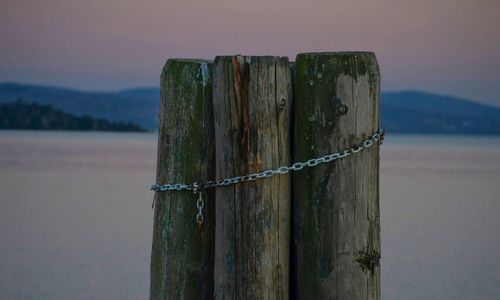 Wooden post in lake against sky