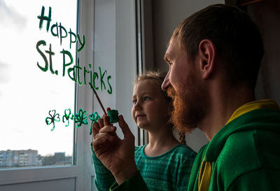 Drawing st. patrick's day father daughter painting green three-leaved shamrocks.stay home new normal