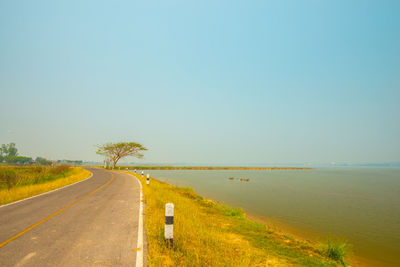 Road by sea against clear sky