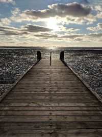 Pier over sea against sky during sunset