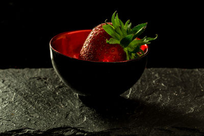 Close-up of red bowl on table against black background