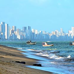 Boats in sea against buildings in city