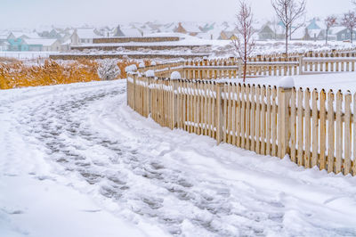 Snow covered field by fence